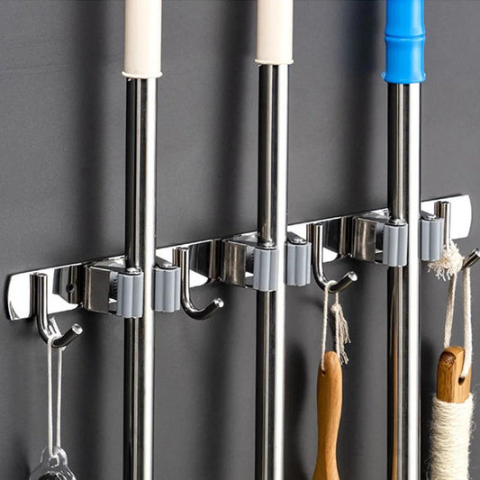 Suporte organizador de vassouras e utensílios domésticos feito em aço inoxidável, com ganchos ajustáveis e presilhas firmes. Ideal para economizar espaço e manter utensílios de limpeza organizados de forma prática e acessível no dia a dia.